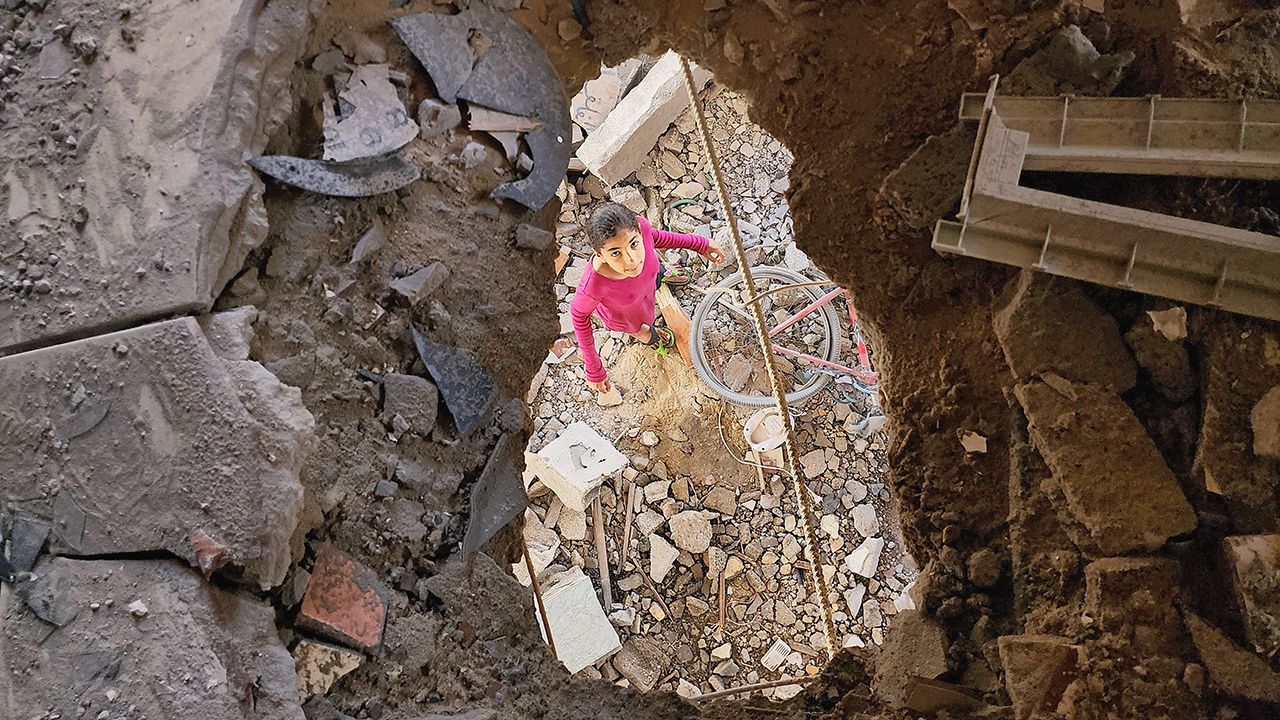 Palestinians, including children, collect remaining belongings from the rubble of destroyed houses in Rafah after Israeli attacks