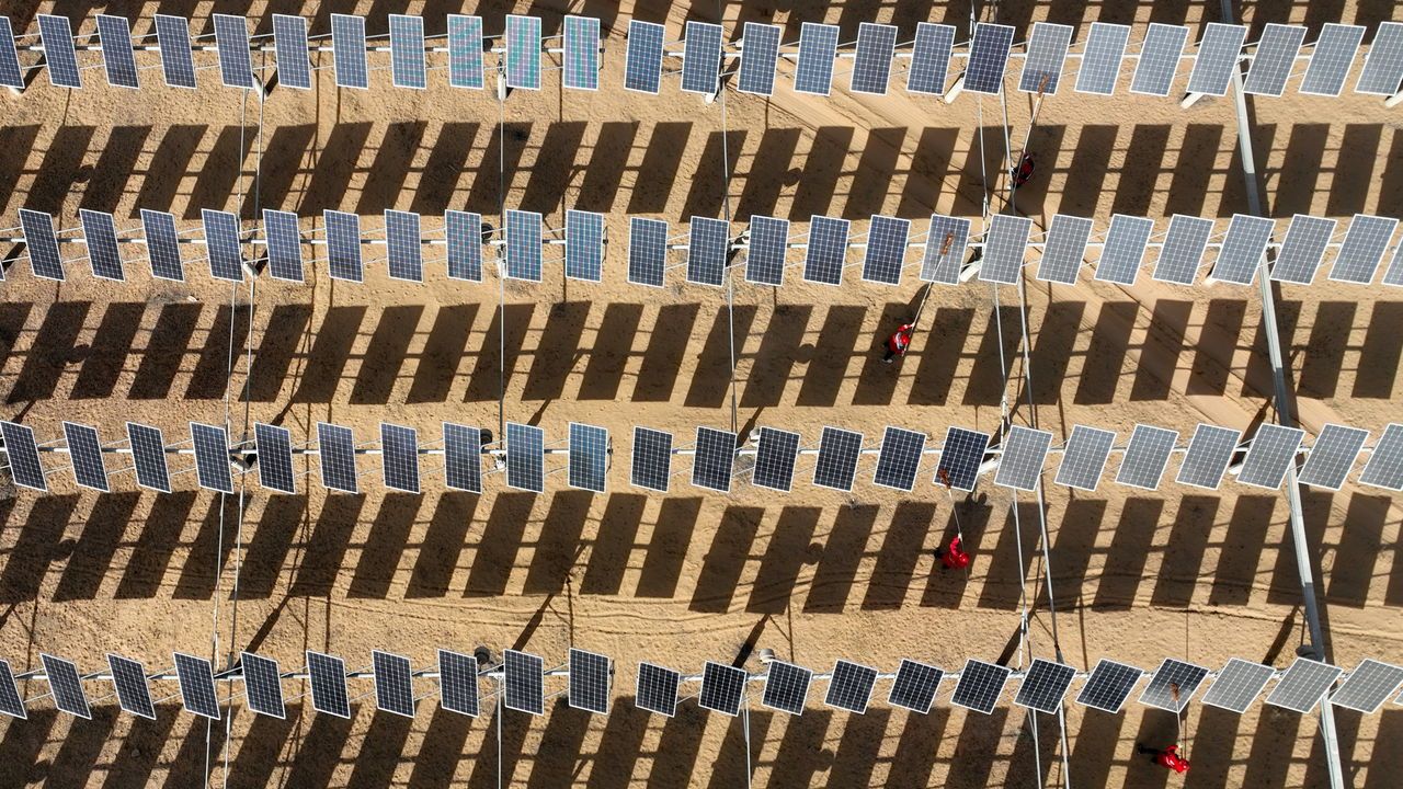 Aerial view of workers cleaning up solar panels at a photovoltaic power station in the Gobi desert