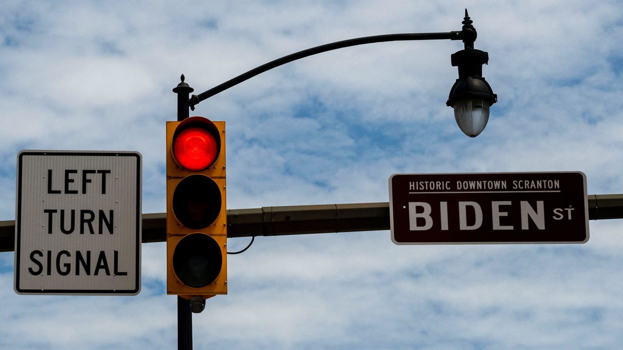 A red light next to a road sign saying “Biden Street”