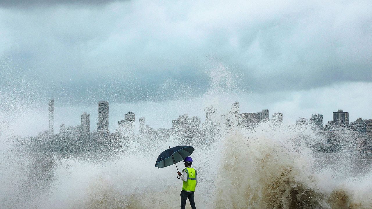 A construction worker watches as waves crash at the seafront in Mumbai, India