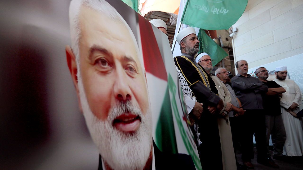 Hamas members stand next to a poster of Hamas political chief Ismail Haniyeh during a protest to condemn his killing