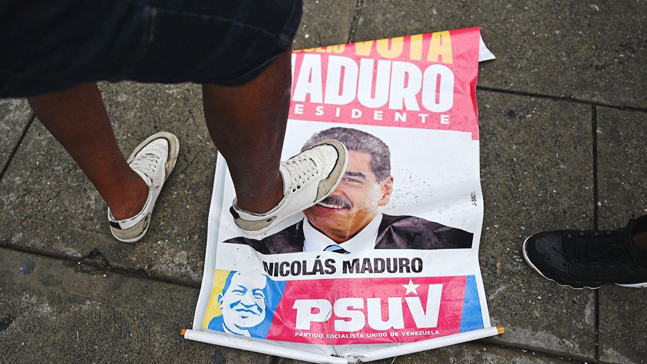 An opponent of Venezuelan President Nicolas Maduro's government steps on an election campaign poster